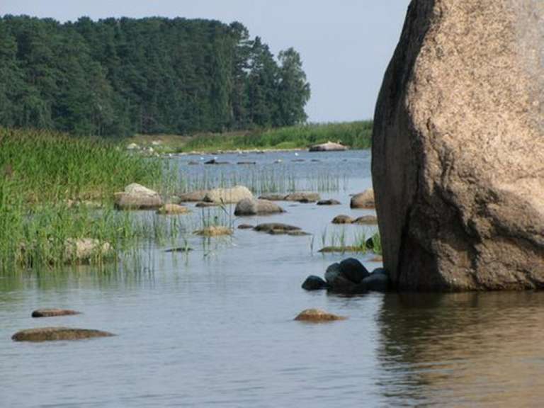 Ein großer Felsen sitzt in der Mitte eines Sees .
