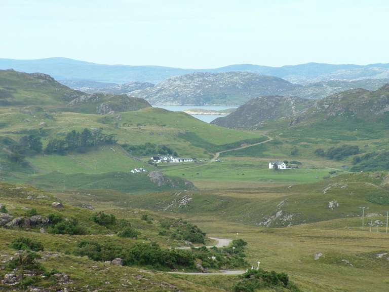 Eine Straße führt durch eine grüne Landschaft mit Bergen im Hintergrund