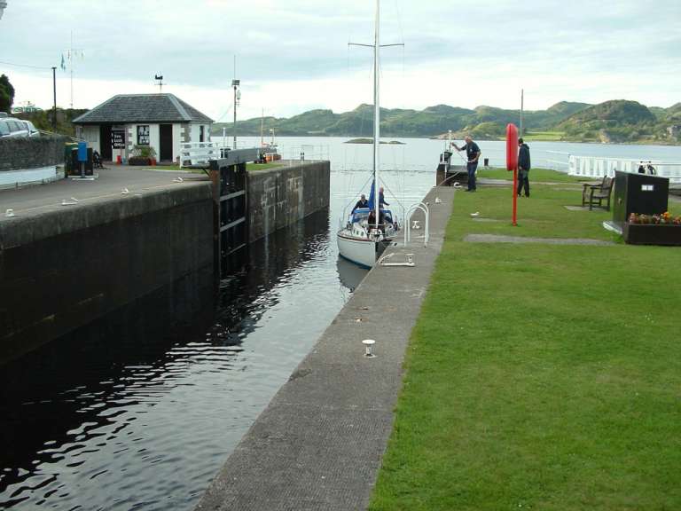 Ein kleines weißes Boot fährt durch eine Schleuse