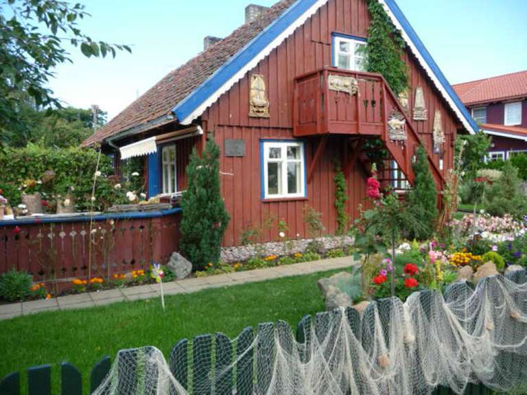Ein rotes Holzhaus mit blauen Fenstern und einem Balkon