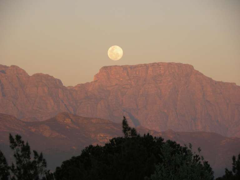 Ein Vollmond steigt über einen Berg