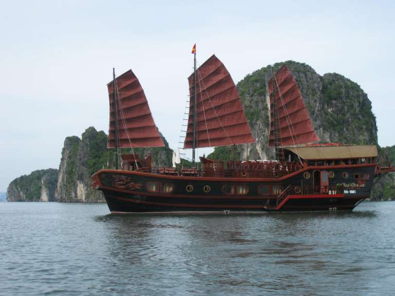 Ein schwarzes und rotes Boot mit roten Segeln schwimmt im Ozean