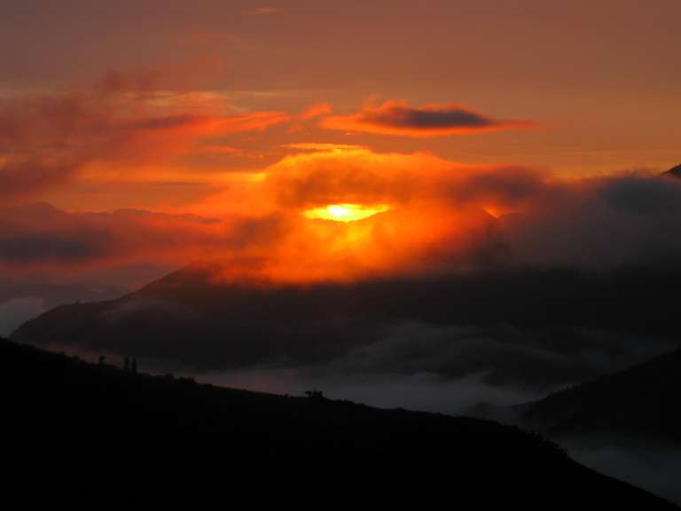 Die Sonne scheint durch die Wolken über den Bergen