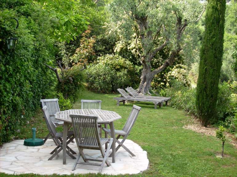 Ein Garten mit einem Tisch und Stühlen und Liegestühlen