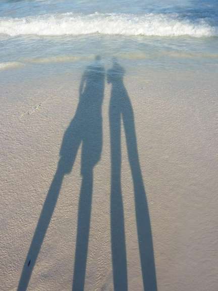 Die Schatten eines Mannes und einer Frau stehen auf einem Strand