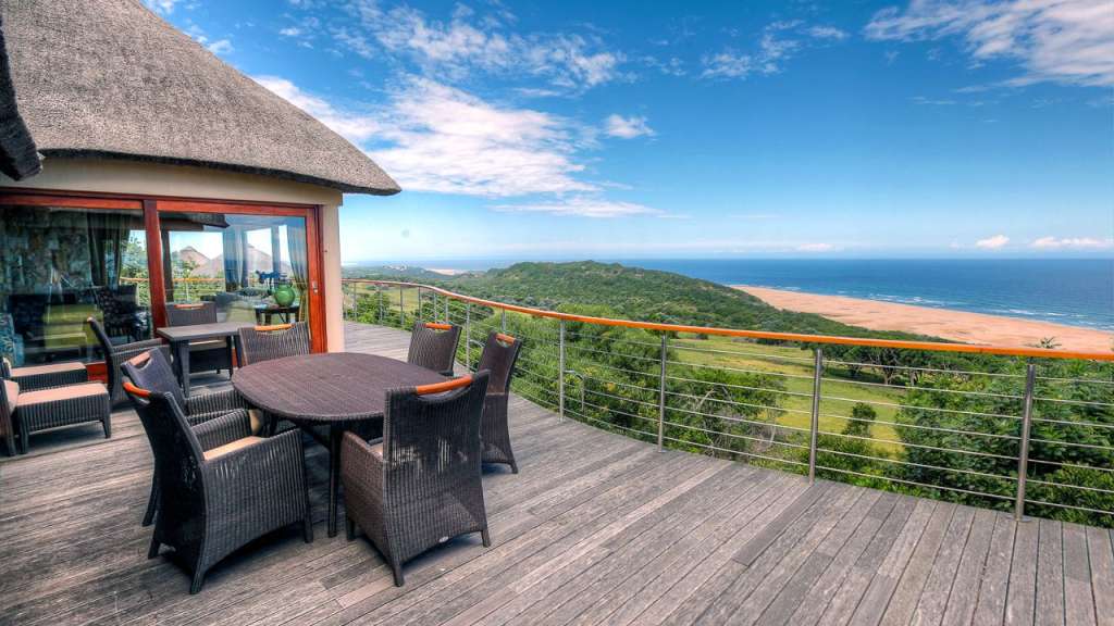 Ein Tisch und Stühle auf einem Holzdeck mit Blick auf das Meer