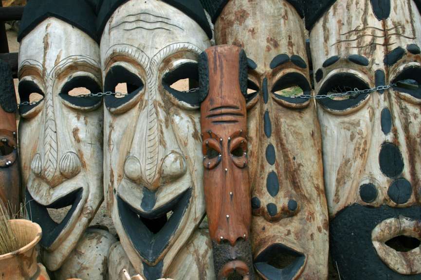 Eine Reihe von Holzmasken steht nebeneinander
