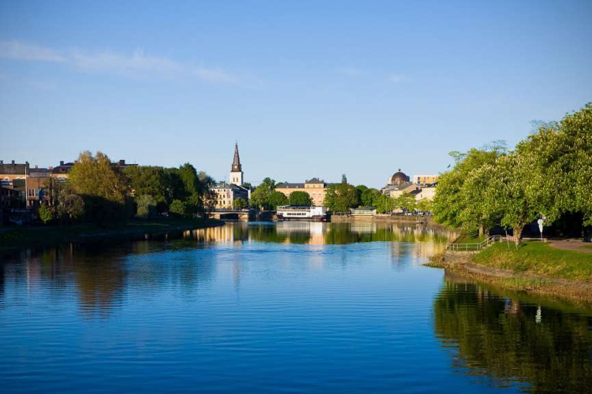 Ein Fluss mit Bäumen und Gebäuden im Hintergrund