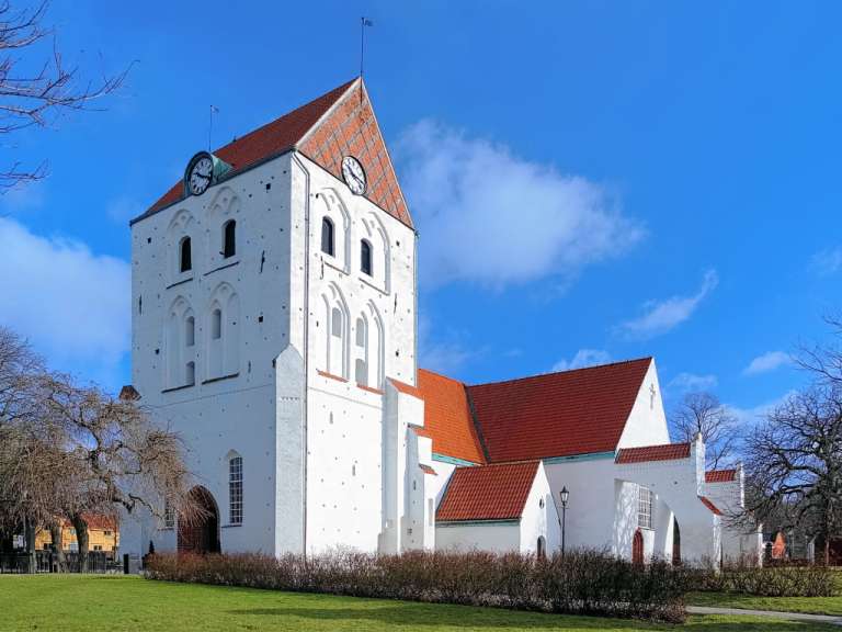 Eine weiße Kirche mit einem roten Dach und einem Uhrturm