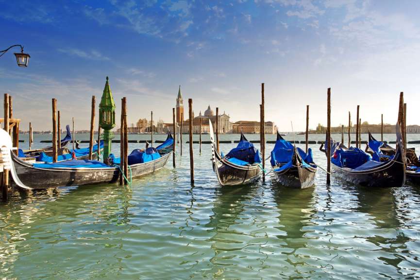Eine Reihe von Booten, die an Holzpfosten im Wasser festgemacht sind