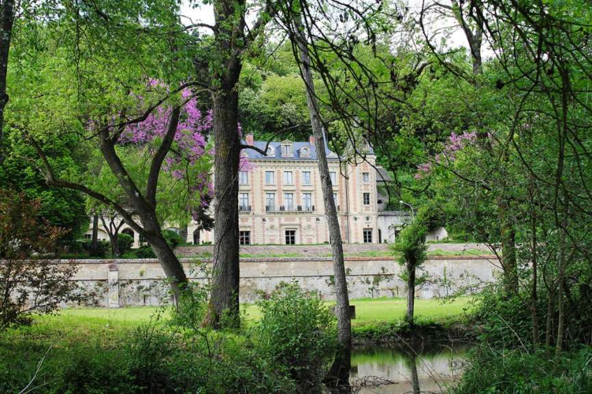 Ein großes Gebäude inmitten eines Waldes mit einem Fluss im Vordergrund