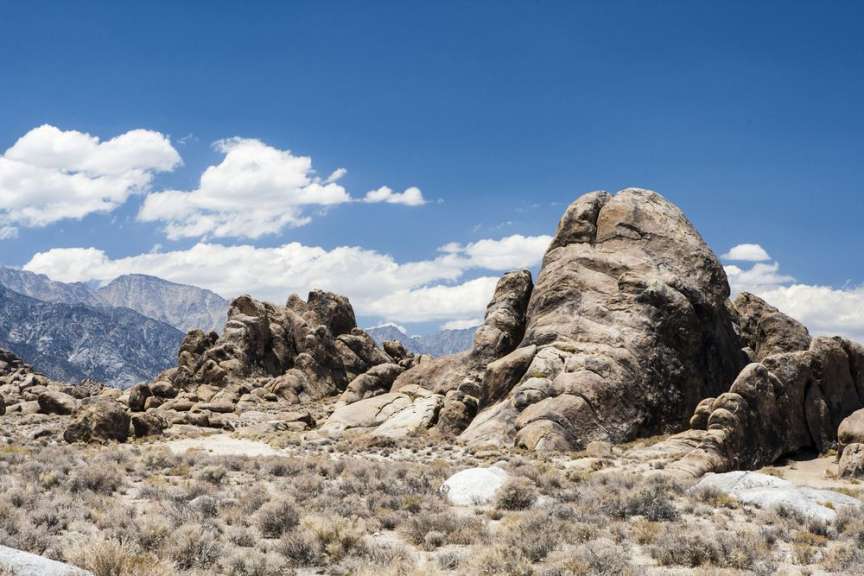 Ein großer Felsen in der Wüste mit Bergen im Hintergrund