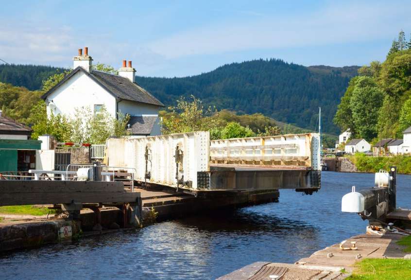 Eine Brücke über einen Fluss mit einem Haus im Hintergrund