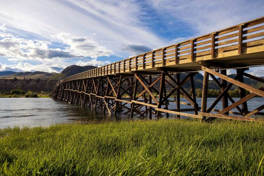 Eine Holzbrücke über einen Fluss mit Bergen im Hintergrund