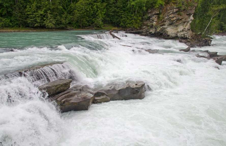 Ein Wasserfall in einem Fluss mit Felsen im Vordergrund