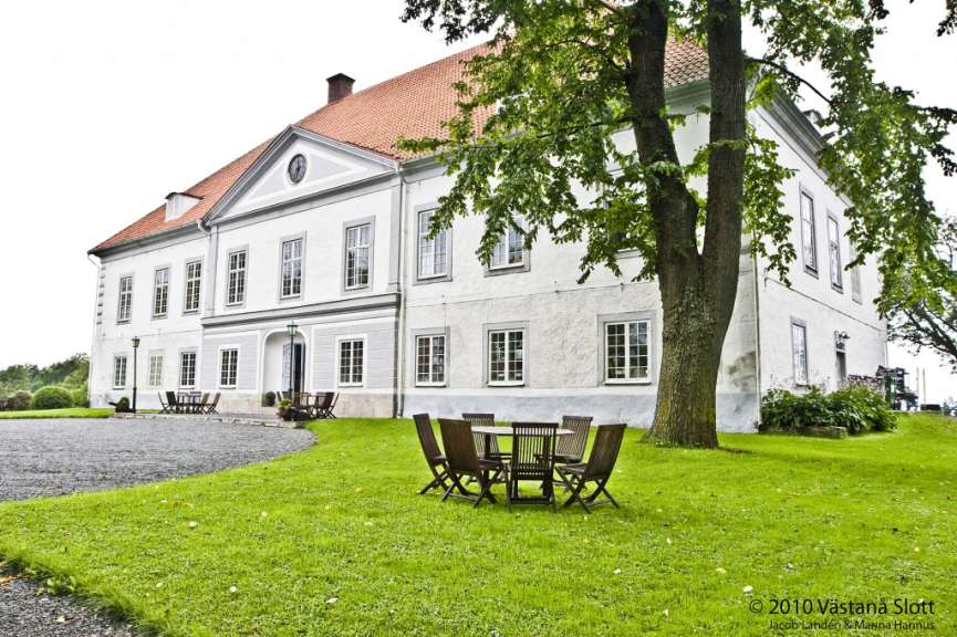 Ein großes weißes Gebäude mit einem Tisch und Stühlen davor