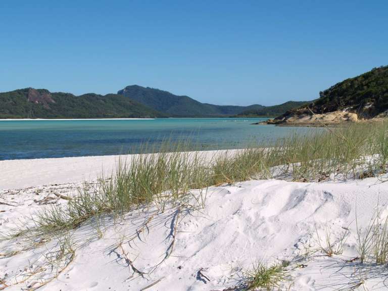 Ein weißer Sandstrand mit einem türkisfarbenen Ozean im Hintergrund