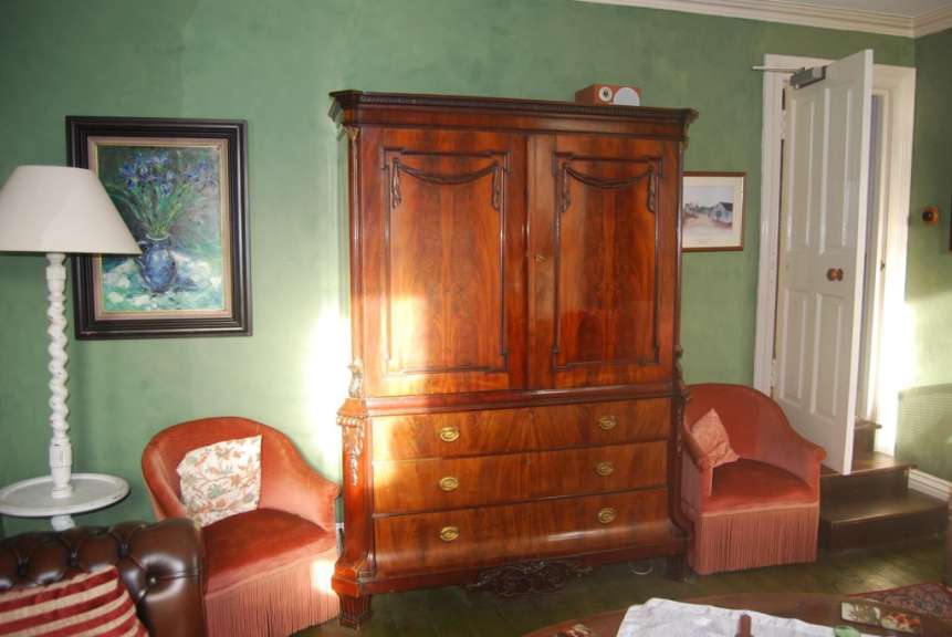 Ein Wohnzimmer mit grünen Wänden und einem großen Holzschrank