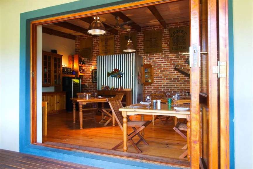 Ein Blick in ein rustikales Restaurant mit Holztischen, Backsteinwänden und Holzbalken an der Decke.