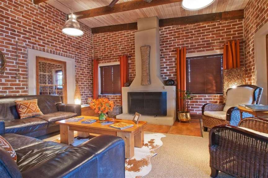 Ein Wohnzimmer mit Backsteinwänden, einem Kamin, Ledersofas und Korbstühlen.