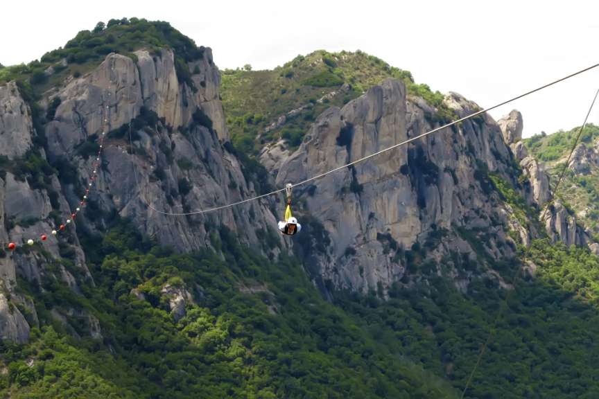 Eine Person fliegt auf einer Seilbahn über einen Berg