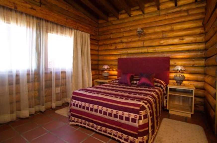 Ein Schlafzimmer in einem Blockhaus mit einem Bett und zwei Nachttischen
