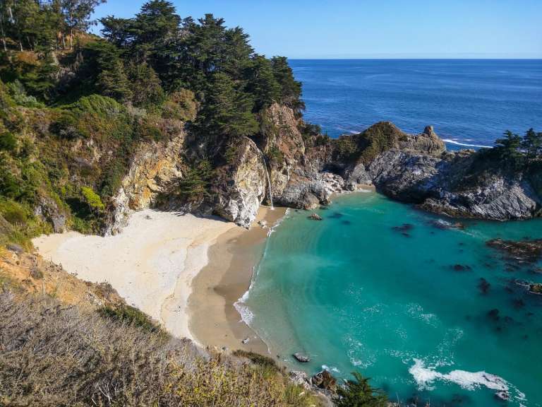 Ein Strand mit einem Wasserfall im Hintergrund