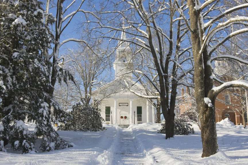 Eine schneebedeckte Kirche mit Bäumen im Vordergrund