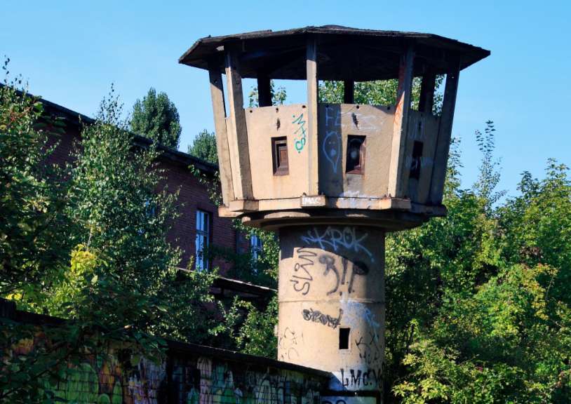 Ein Turm mit Graffiti darauf steht neben einem Zaun