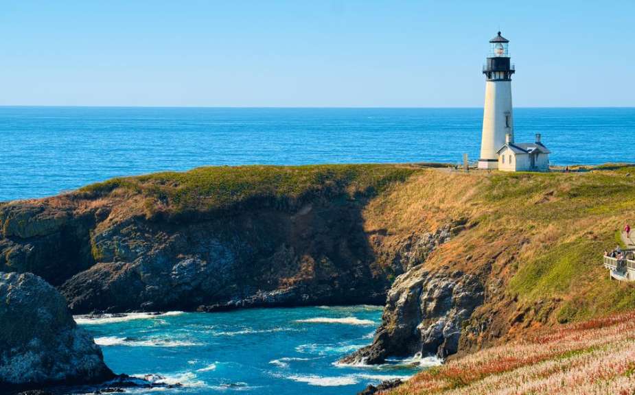 Ein Leuchtturm steht auf einer felsigen Klippe mit Blick auf das blaue Meer.