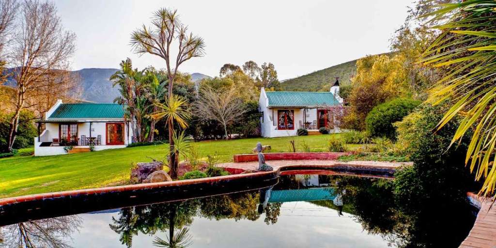 Ein weißes Haus mit einem grünen Dach steht neben einem Teich