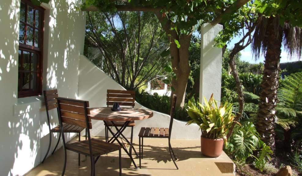 Ein Tisch und Stühle auf einer Terrasse neben einem Baum