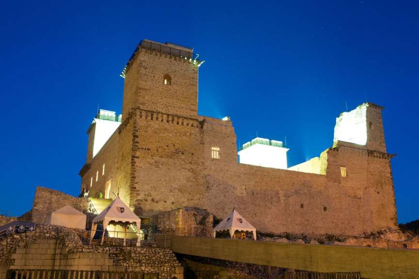 Ein großes mittelalterliches Schloss beleuchtet in der Nacht