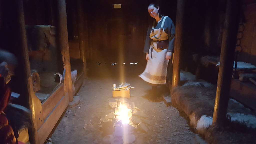 Eine Frau steht vor einem Feuer in einem dunklen Raum