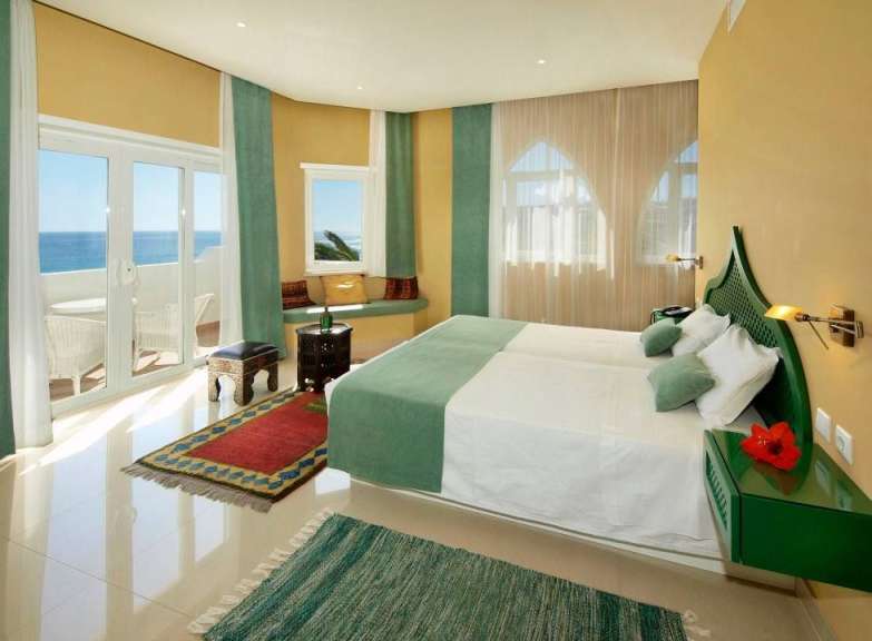 Ein Schlafzimmer mit einem Bett und einem Fenster mit Blick auf das Meer