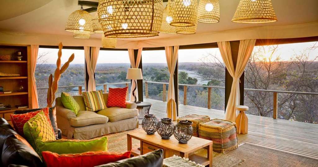 Ein Wohnzimmer mit vielen Möbeln und einem Balkon mit Blick auf einen Fluss