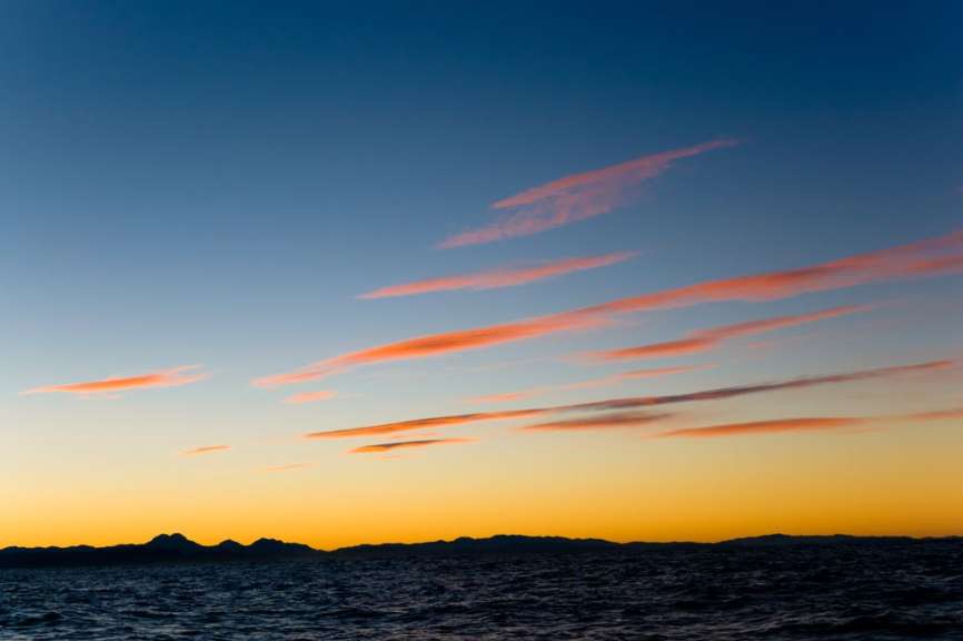 Ein Sonnenuntergang über dem Ozean mit Bergen im Hintergrund
