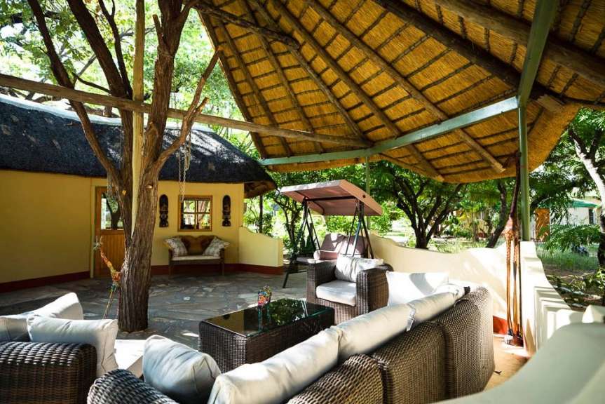 Eine überdachte Veranda mit Sitzgelegenheiten und einem Schaukelsitz im afrikanischen Stil.