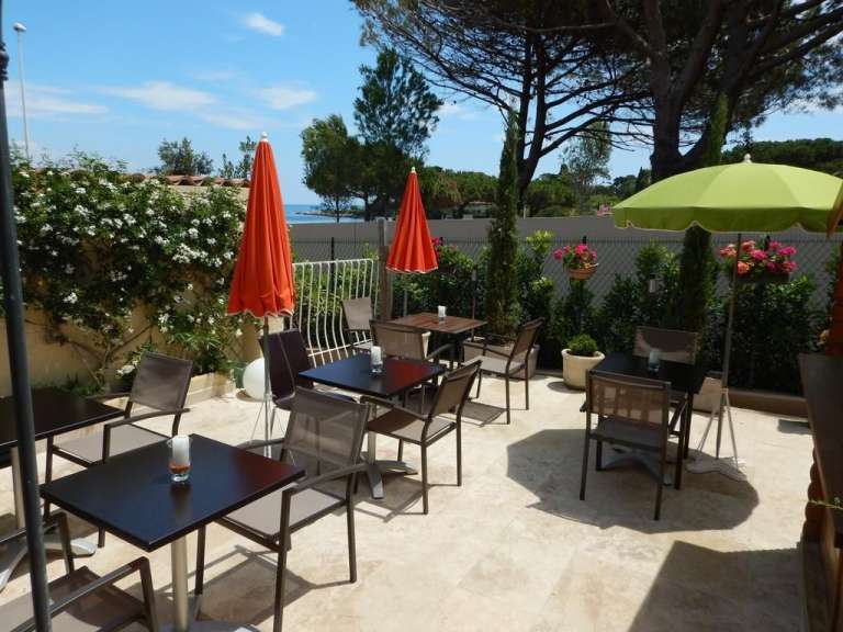 Eine Terrasse mit Tischen und Stühlen und Regenschirmen