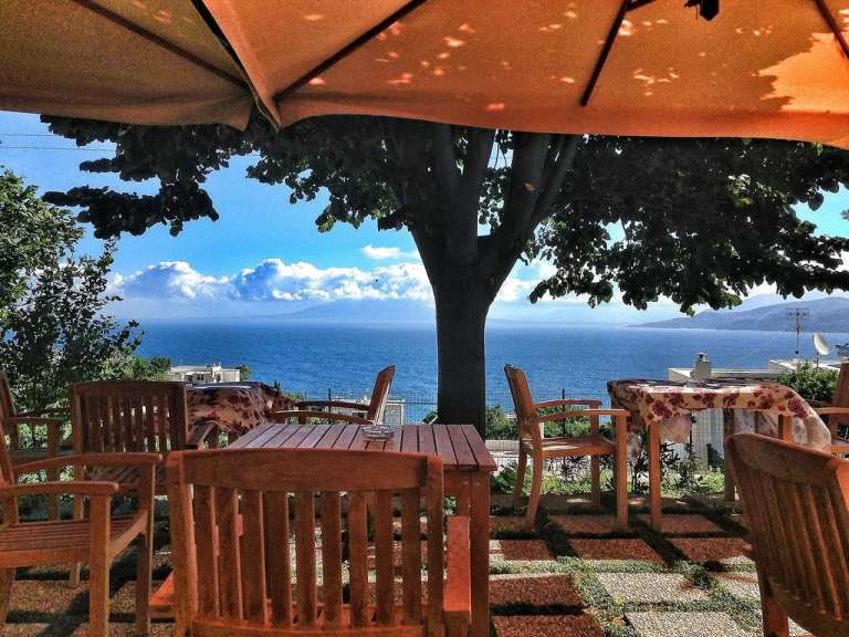 Ein Tisch und Stühle unter einem Sonnenschirm mit Blick auf das Meer