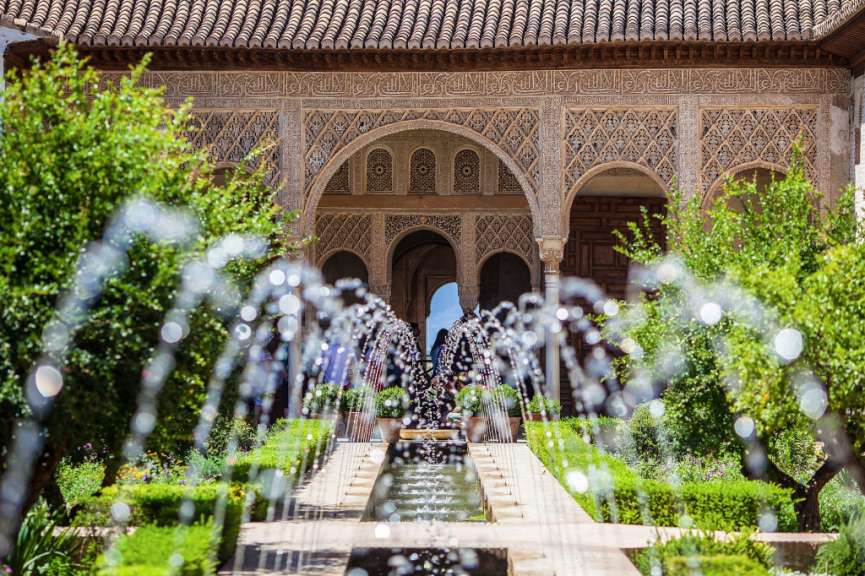 Ein Brunnen in einem Garten mit einem Gebäude im Hintergrund