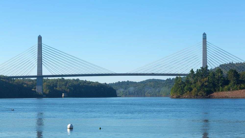 Eine Brücke über einen großen Fluss mit einem weißen Buoy im Vordergrund