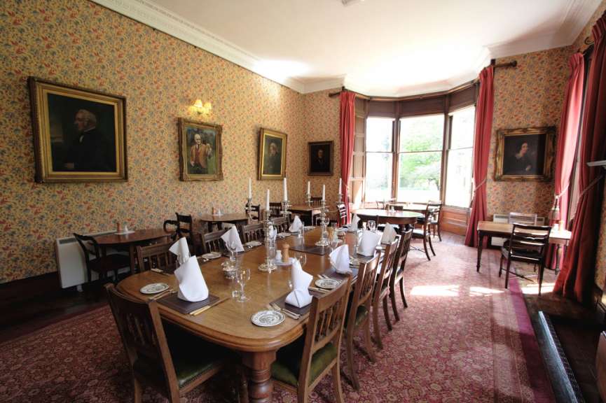 Ein Esszimmer mit Tischen und Stühlen und zwei Gemälden an den Wänden