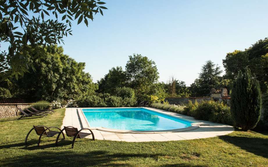 Ein großer Swimmingpool umgeben von Stühlen und Bäumen