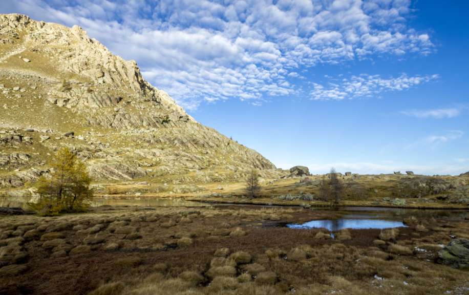 Ein Bergsee mit einem Berg im Hintergrund und einem blauen Himmel mit Wolken
