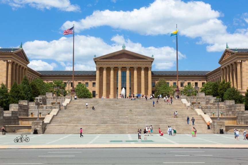 Das Bild zeigt die breiten Treppen des Philadelphia Museum of Art mit vielen Menschen, die die Stufen hinauf- und hinuntergehen.