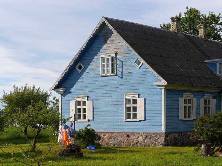 Ein blaues Holzhaus mit weißen Fensterläden und einem schwarzen Dach