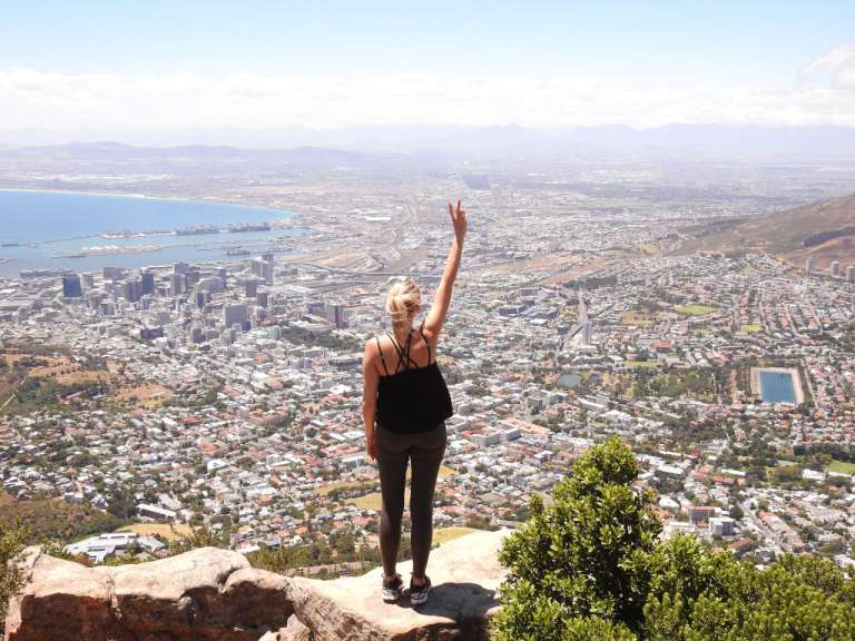 Eine Frau steht auf einem Felsen und zeigt auf eine Stadt