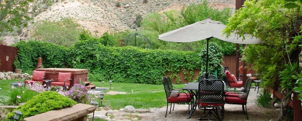 Ein garten mit einem tisch und stühlen und einem schirm