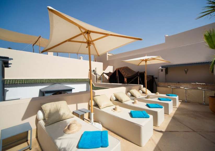 Eine Terrasse mit Liegestühlen und Sonnenschirmen und blauen Handtüchern